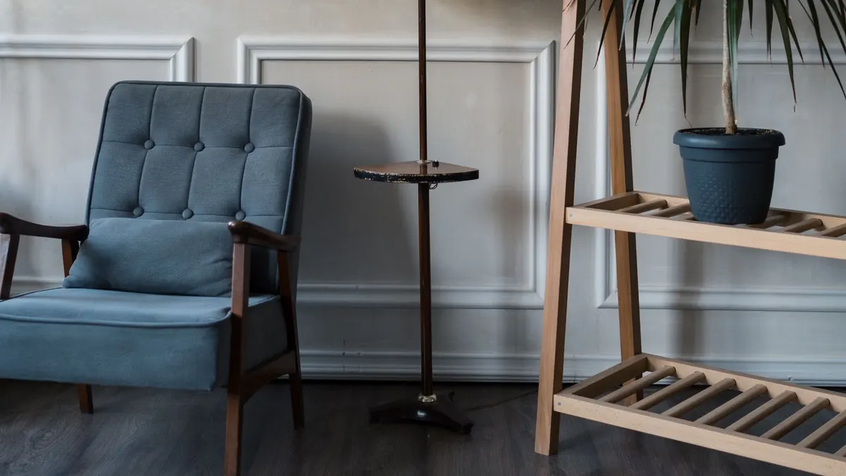 Sillón tapizado junto a una lámpara de pie y una planta en una sala tranquila, como la de una consulta de psicología